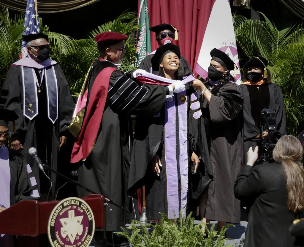 Graduation ceremony with graduates receiving diplomas.