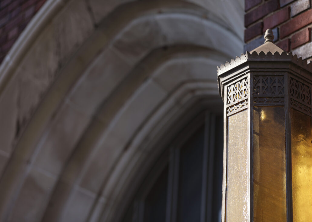 An ornate street lamp in front of a large brick building.