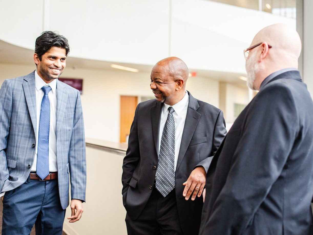 Group of men in suits, posing for photo.