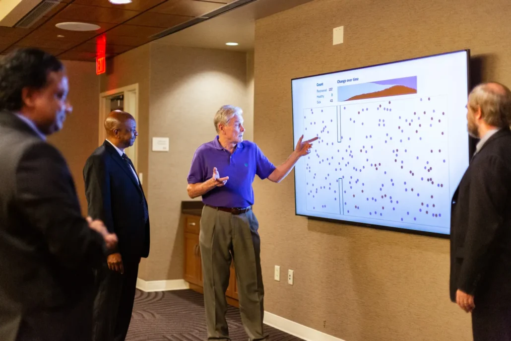 Man pointing at a large screen displaying data.
