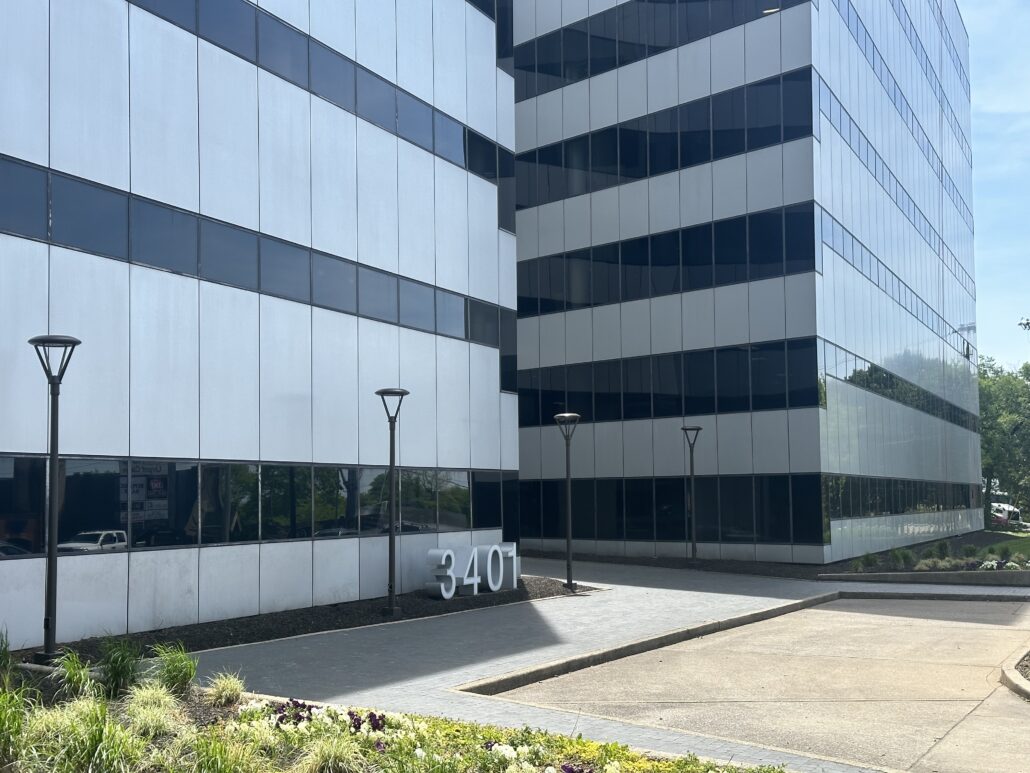 Office building with large windows and a parking lot.