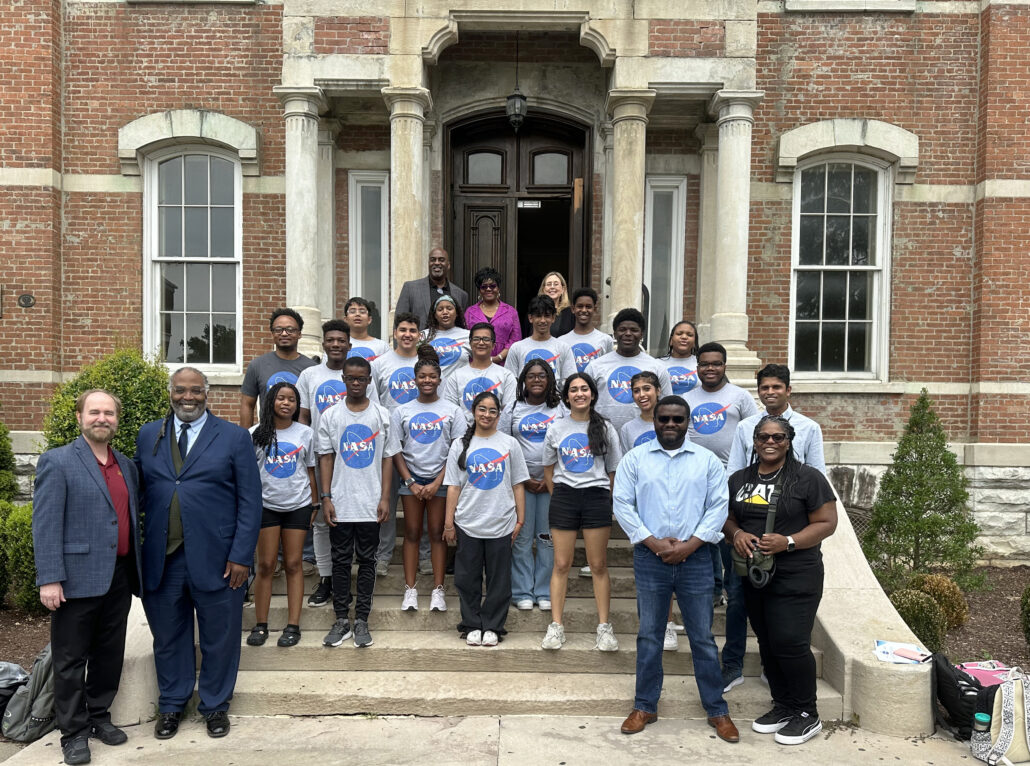 Group of people posing for photo in front of building.