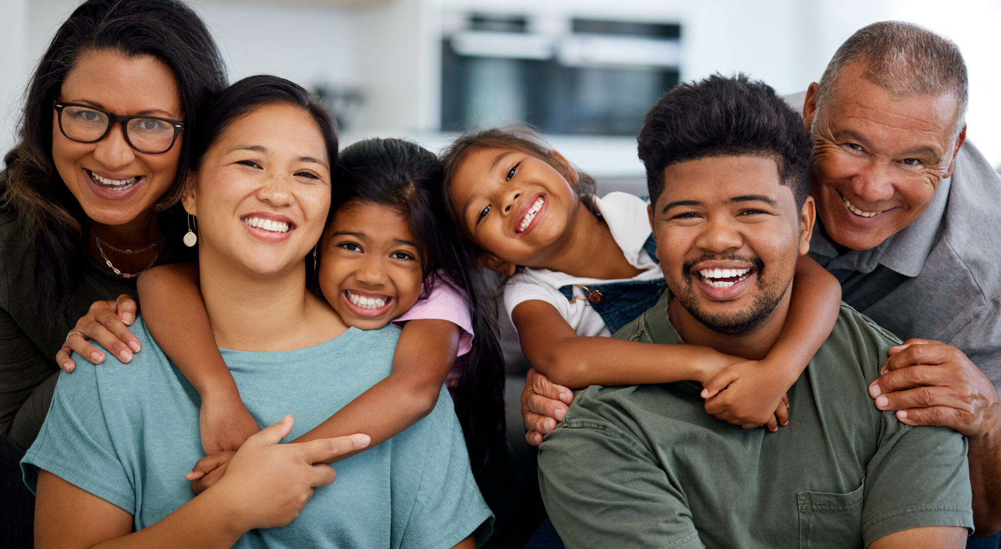 A family of six poses for a photo, smiling and happy.