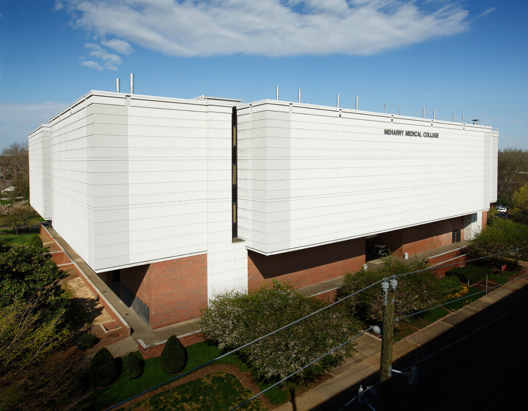 White building with red roof, large windows, and brick foundation.