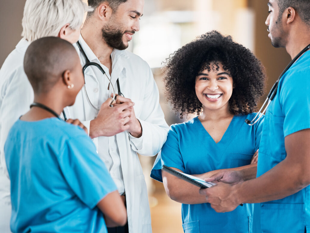 A group of healthcare professionals in a hospital setting, smiling and interacting with each other.