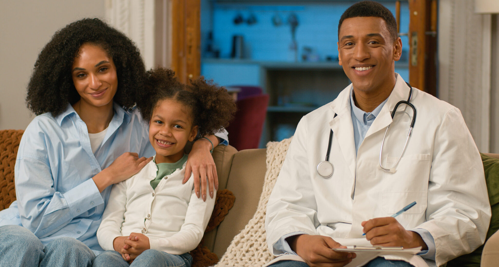 A family posing with a doctor in a living room.