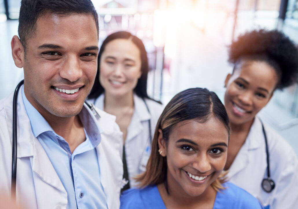 A group of healthcare professionals in a hospital setting, smiling and posing for a photo.