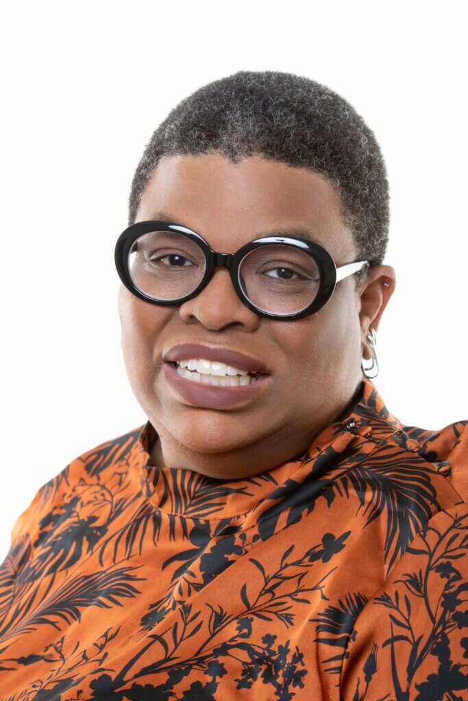 Woman with glasses and short hair, smiling at camera.