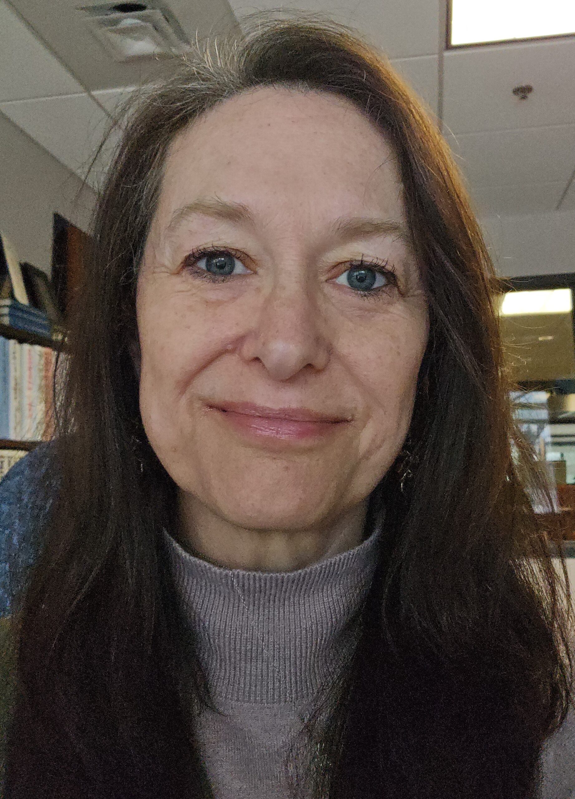 Woman with blue eyes, smiling slightly, against a blurred background.