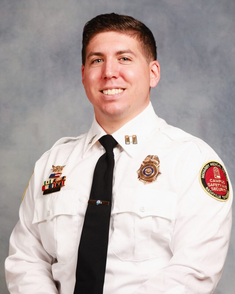 Police officer in uniform standing in front of a wall.