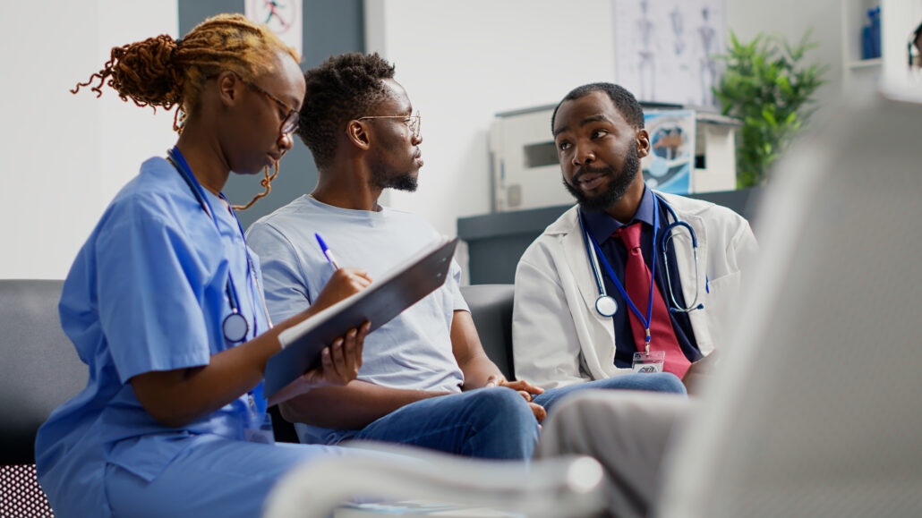 A group of people in a hospital setting, engaged in a discussion.