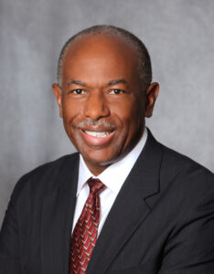 Man in suit, smiling, posing for portrait.