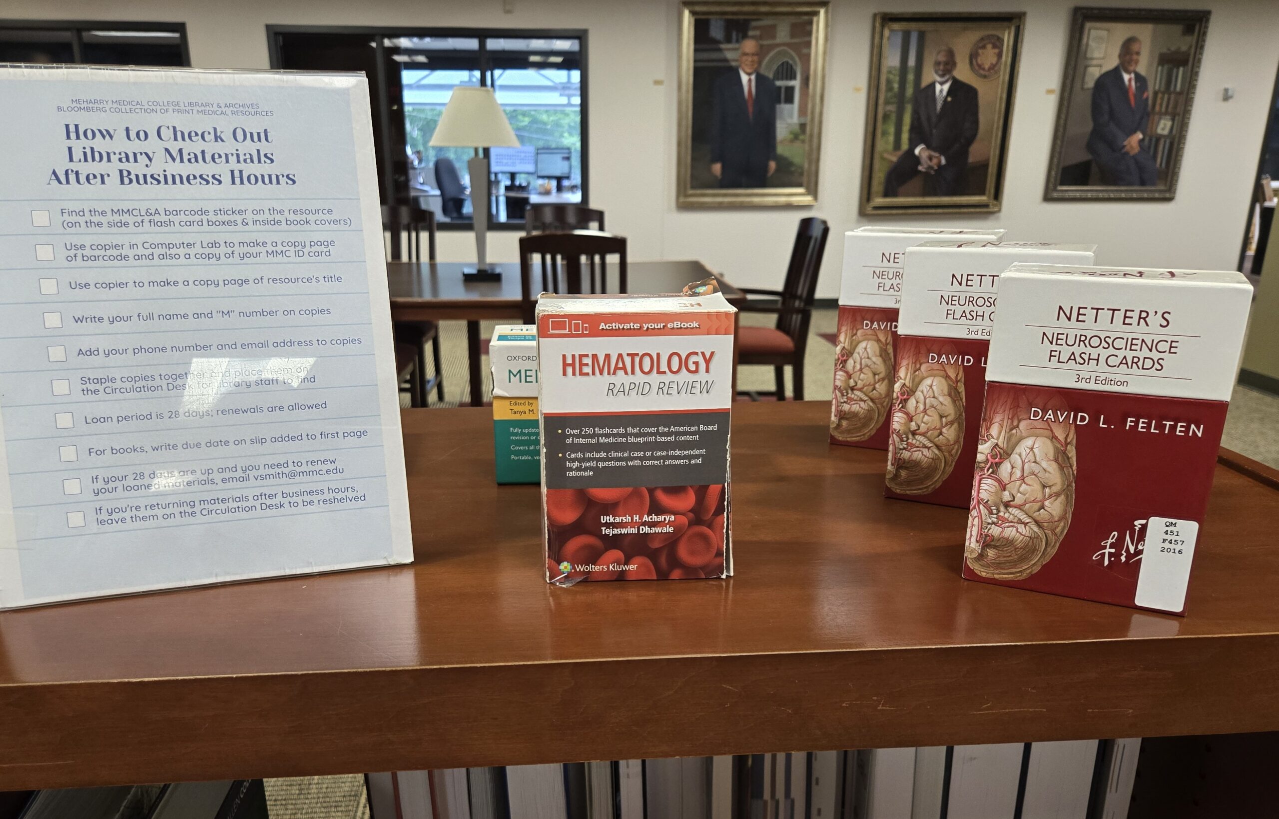 Books on a table, flyer in front of them, library setting.