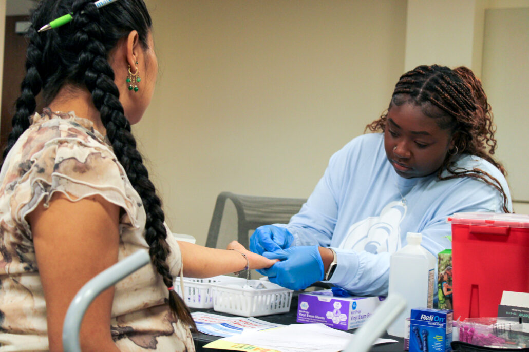 Woman in blue shirt at desk with computer monitor.