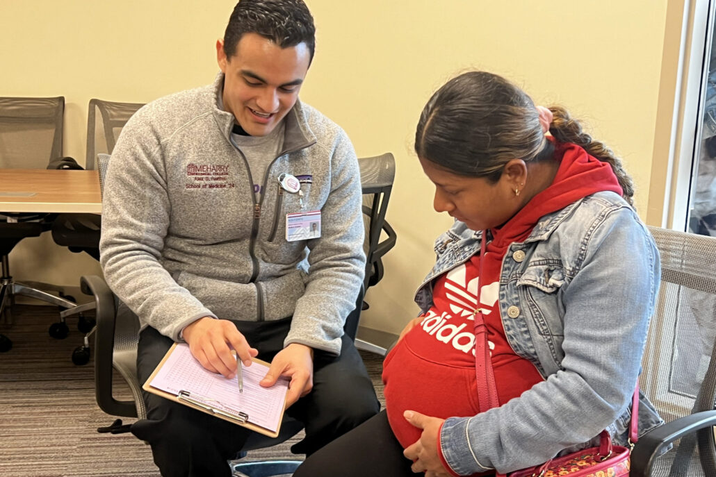 Man in white shirt and black pants standing next to pregnant woman.