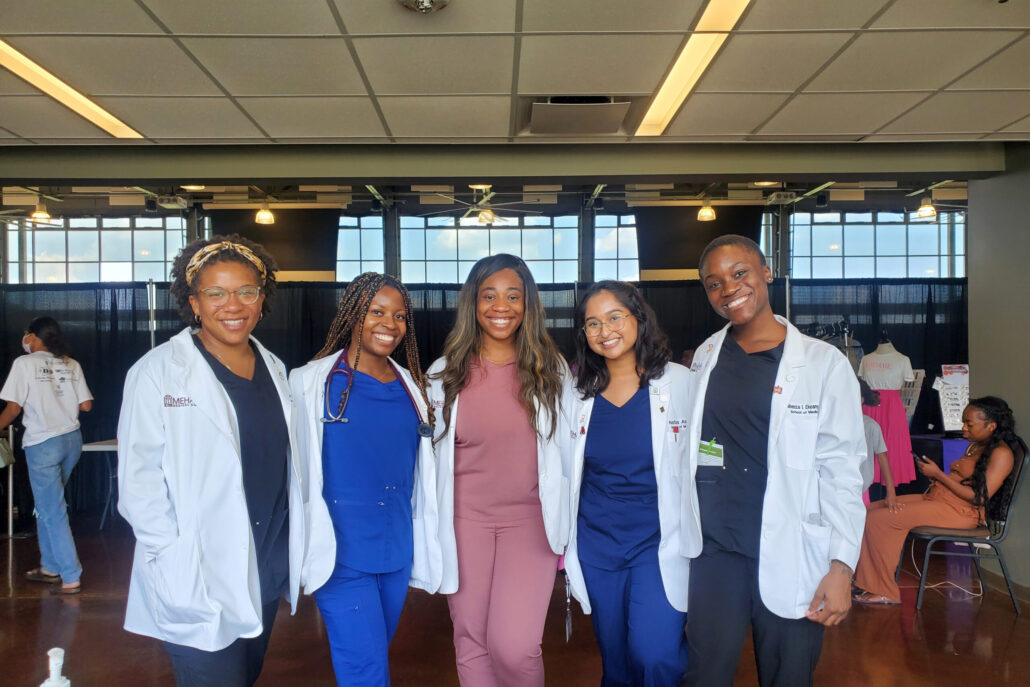 Group of six women in lab coats posing for photo.