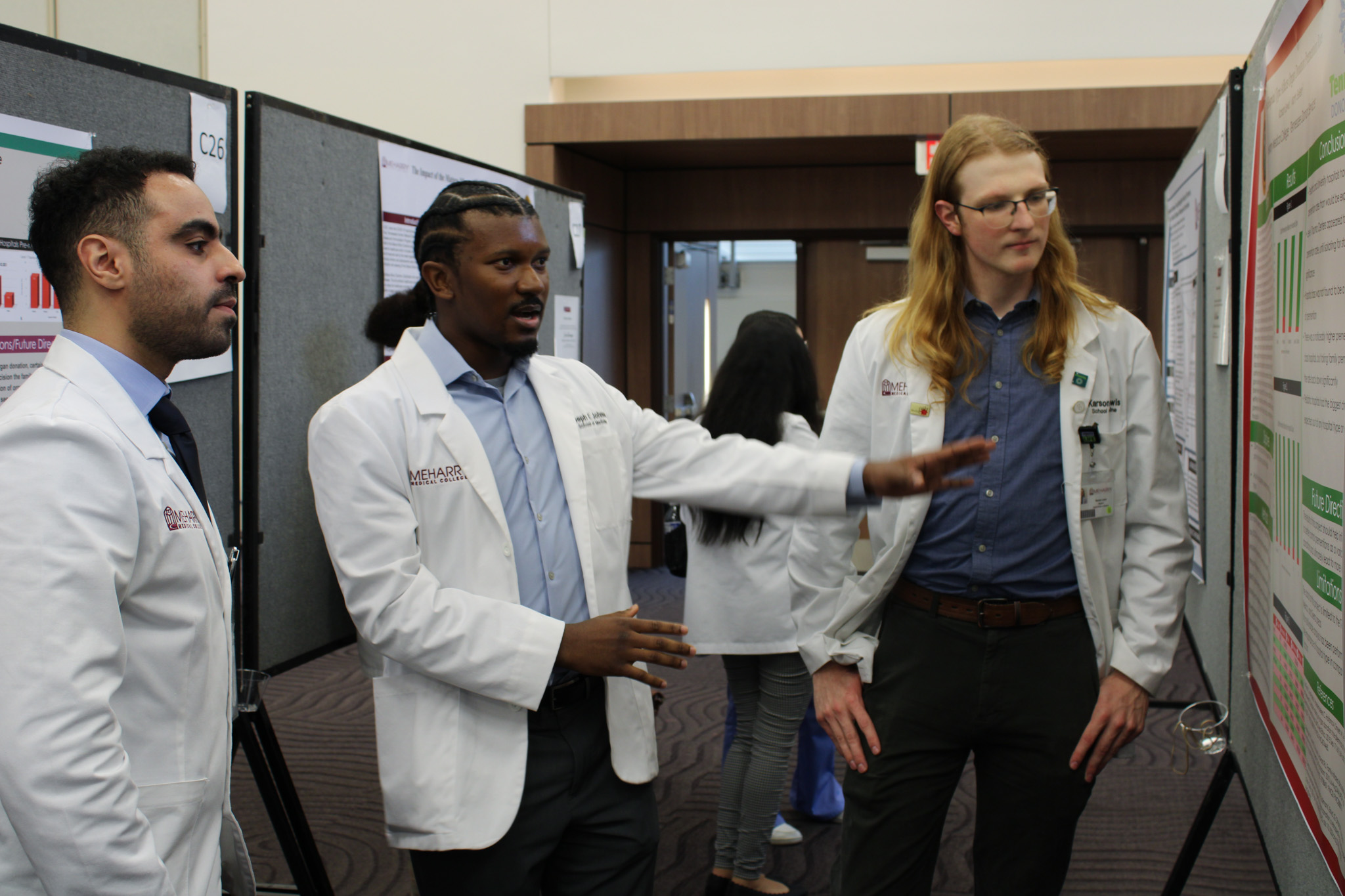 A group of people in a conference room, standing around a table with a board and papers.