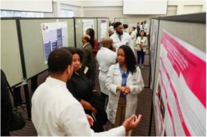 Two photos of a conference room with people standing around a display board, engaged in conversation.