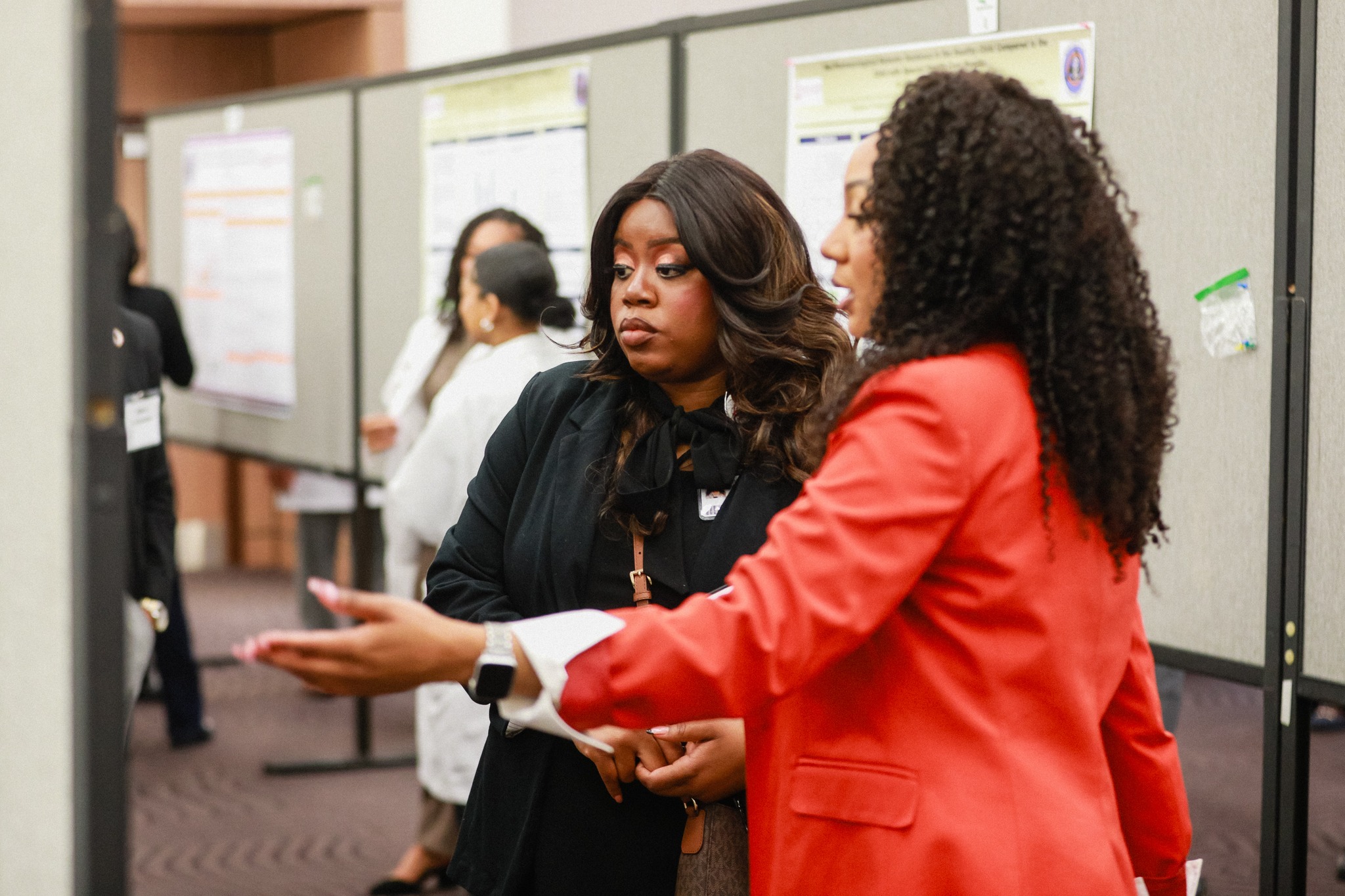 Two women standing in front of a display board, engaged in conversation.