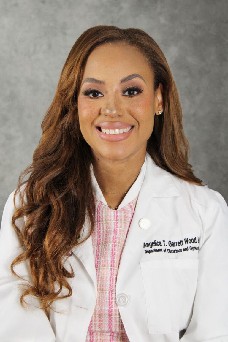 Woman in white coat smiling at camera.