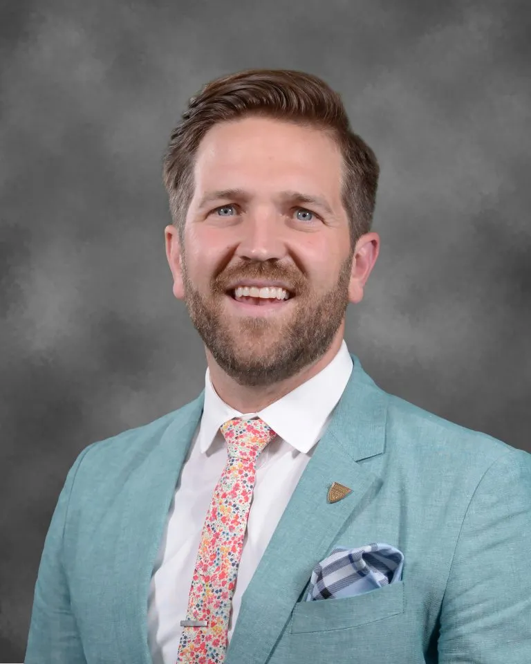 Man in suit, smiling, posing for photo.