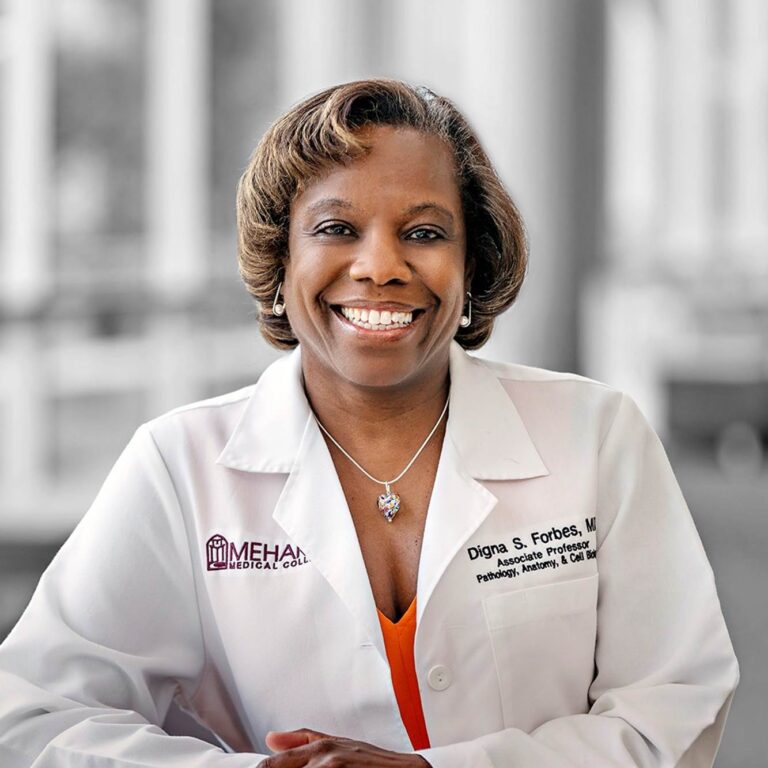 Two women in lab coats, smiling, posing for photo.