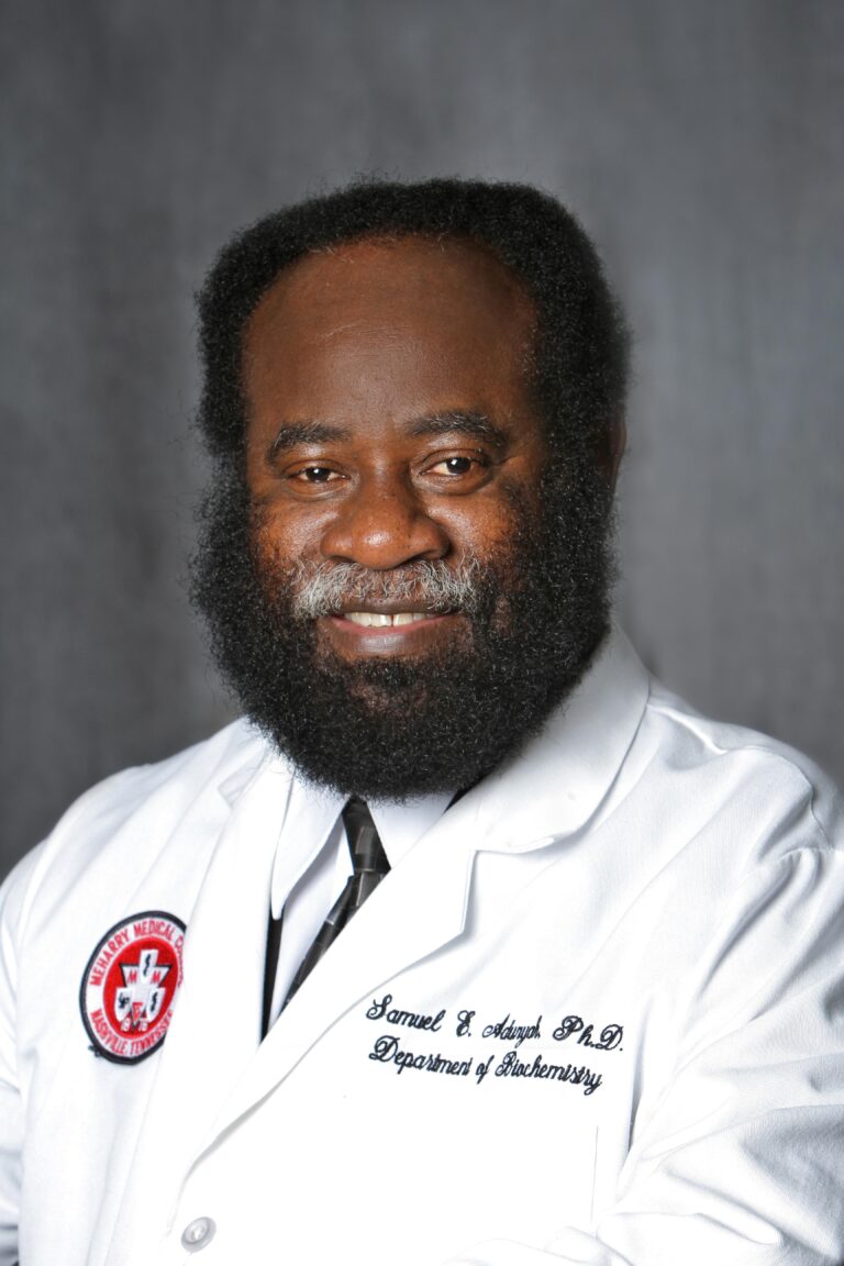 Man in white lab coat, smiling, posing for photo.