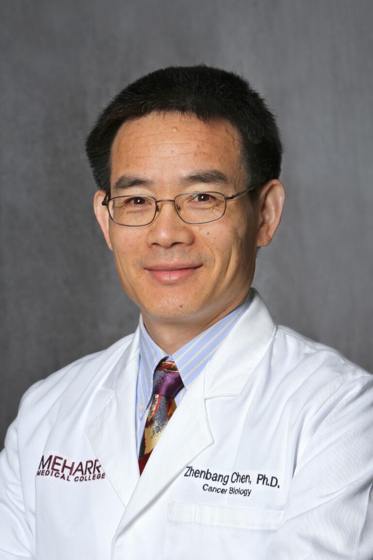 Asian man in white lab coat, smiling, posing for portrait.