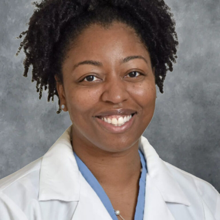 A woman in a white coat, smiling.