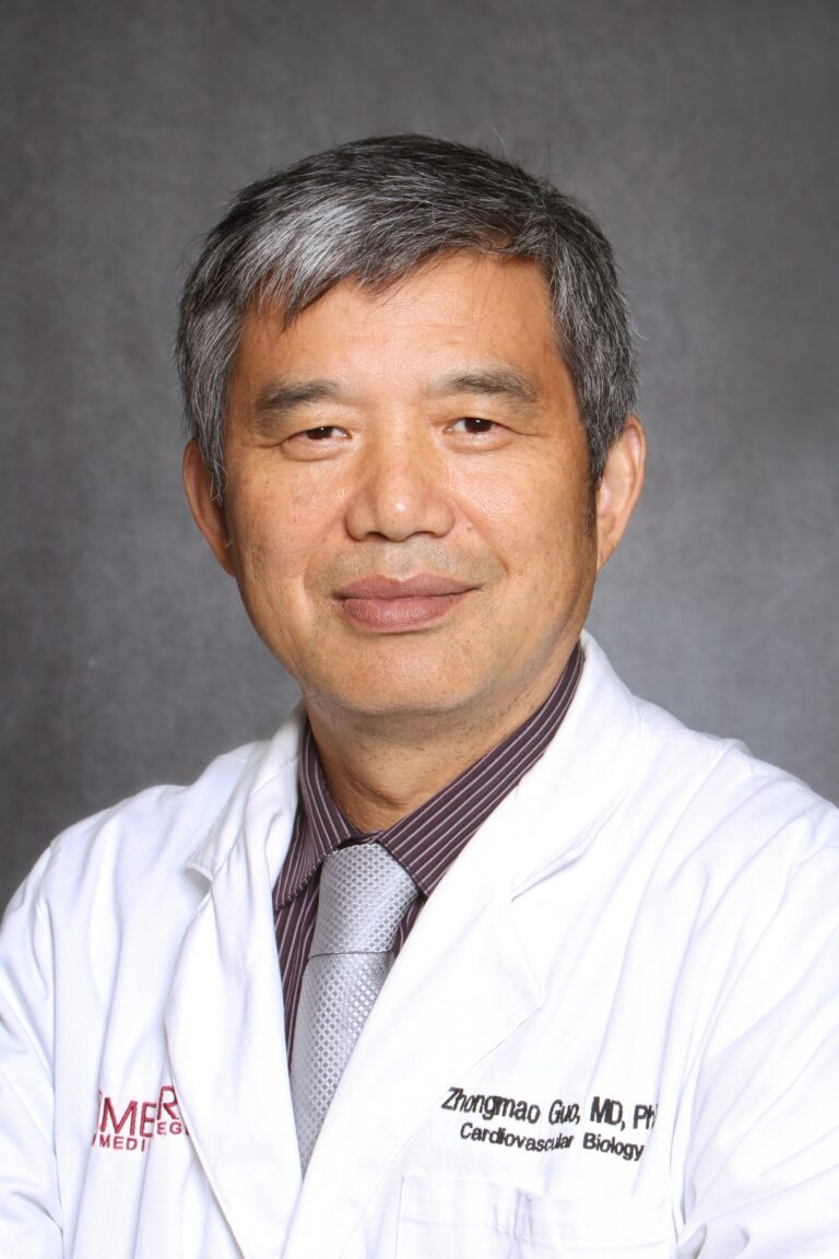 Asian man in white coat posing for portrait.