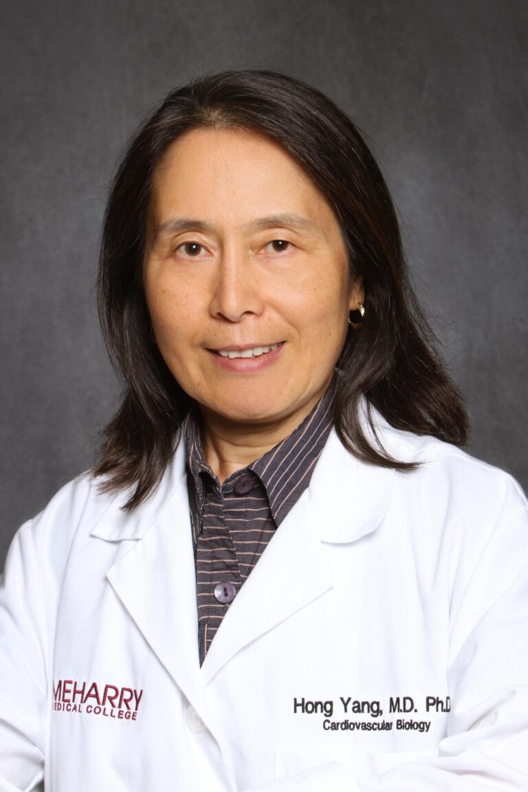 Woman in white lab coat, smiling, posing for portrait.