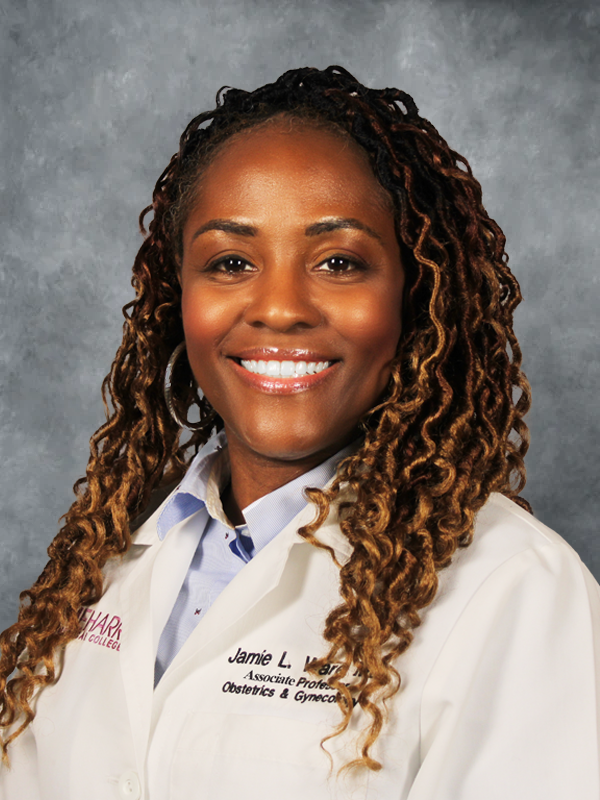 Woman in lab coat smiling at camera.