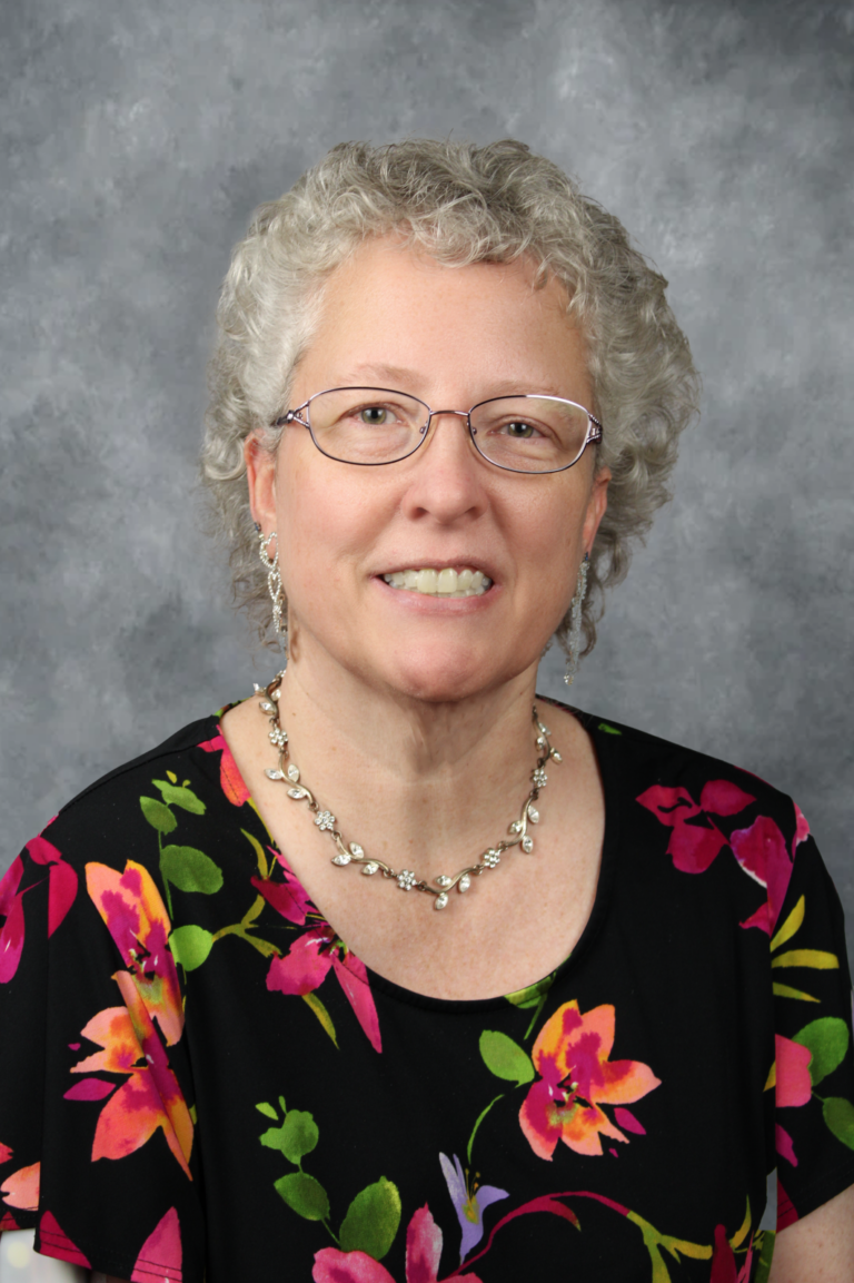 Woman in glasses, smiling, posing for portrait.
