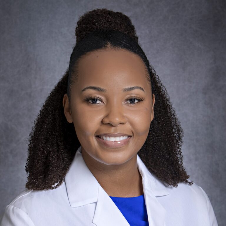 Woman in white coat posing for portrait.