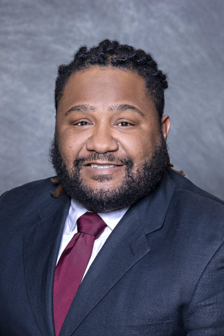 A man in a suit smiling at the camera.