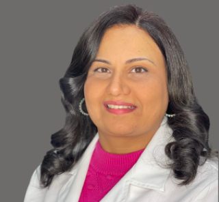 Woman in white coat, smiling, posing for portrait.
