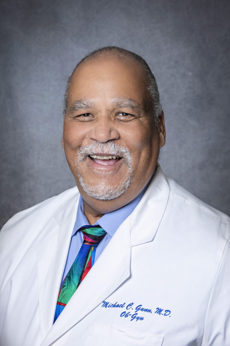 Old man in white coat, smiling, posing for portrait.