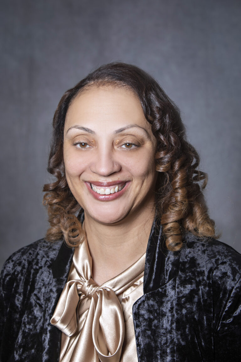 Woman in suit with big smile, posing for portrait.