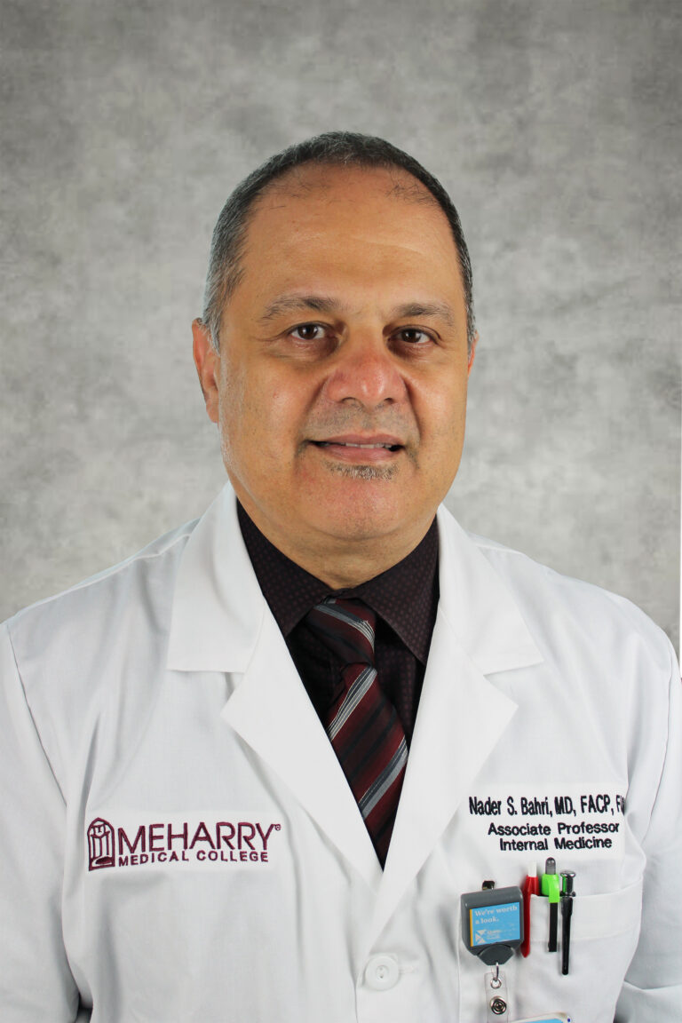 Man in white coat standing in front of camera.