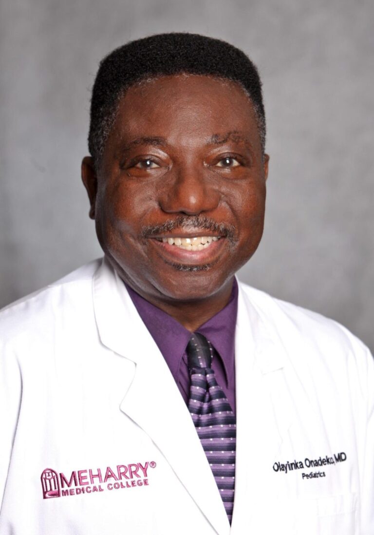Man in white coat smiling at camera.