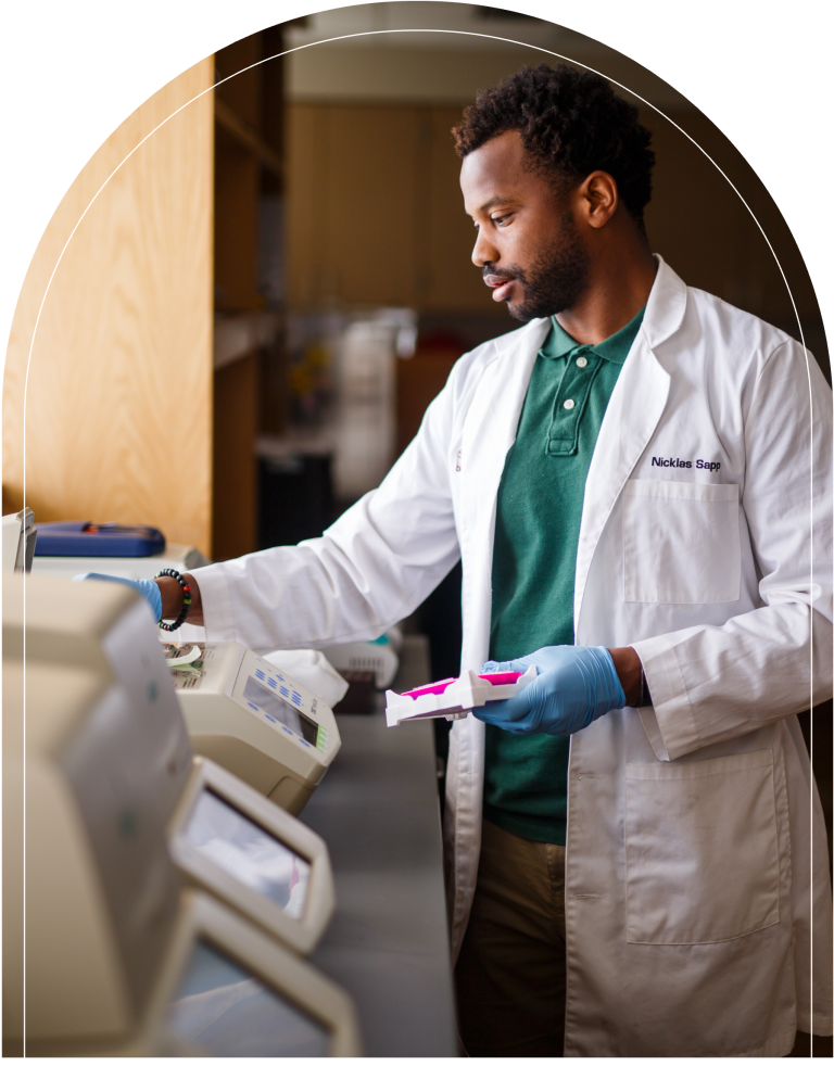 Man in lab coat standing at counter with papers.