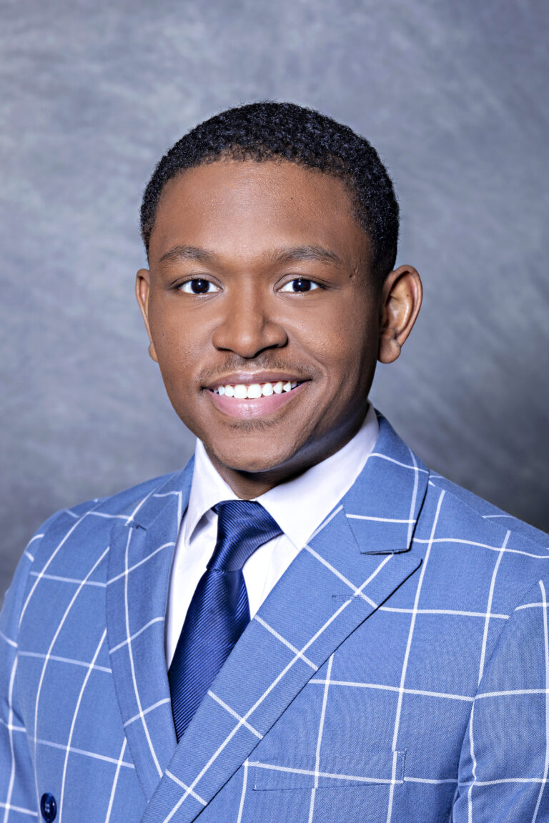 Man in suit smiling, posing for portrait.