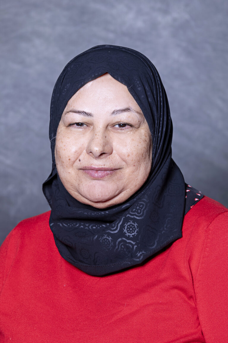 Woman wearing hijab, smiling at camera.
