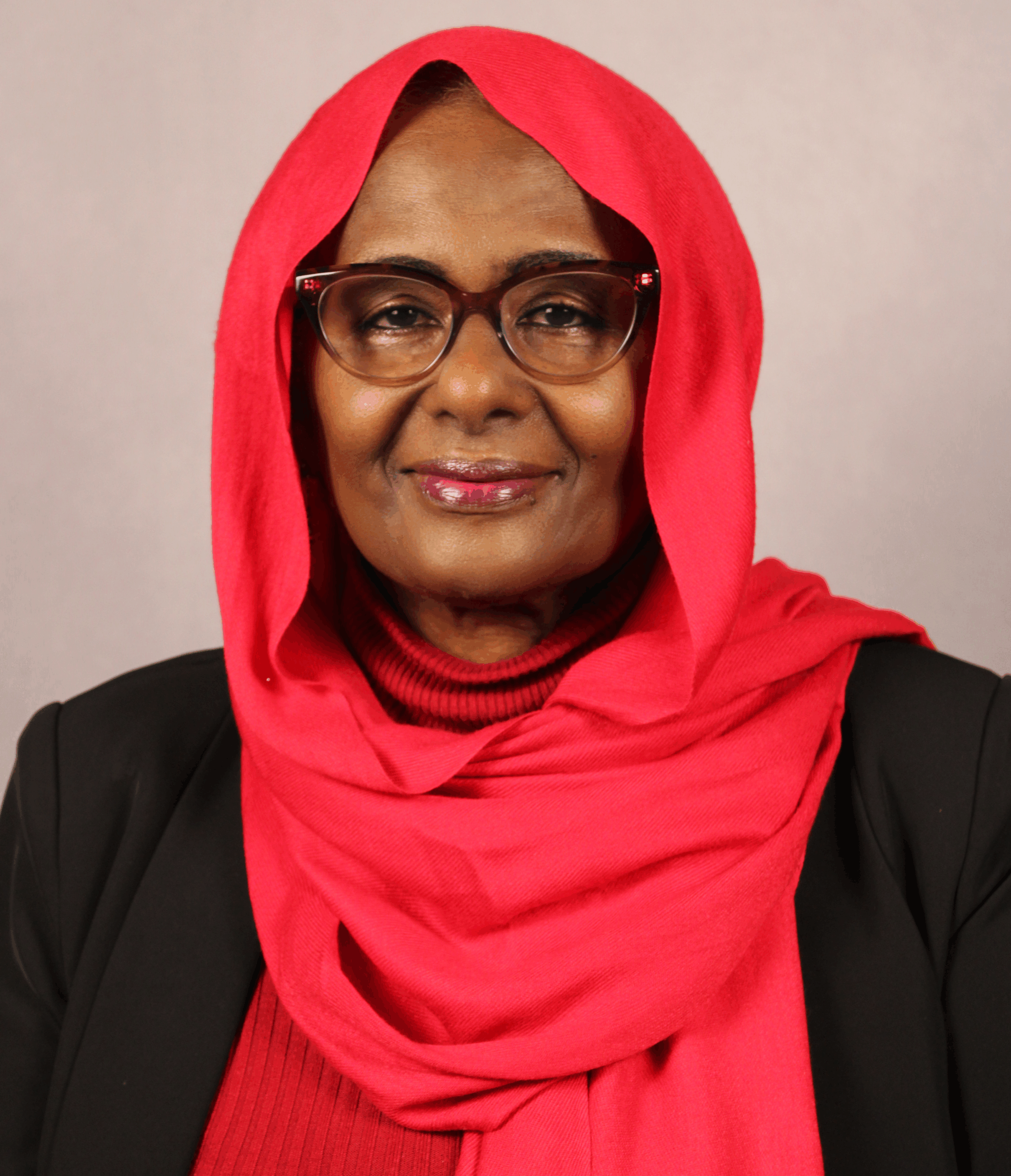 Woman in red hijab and glasses, wearing black jacket.