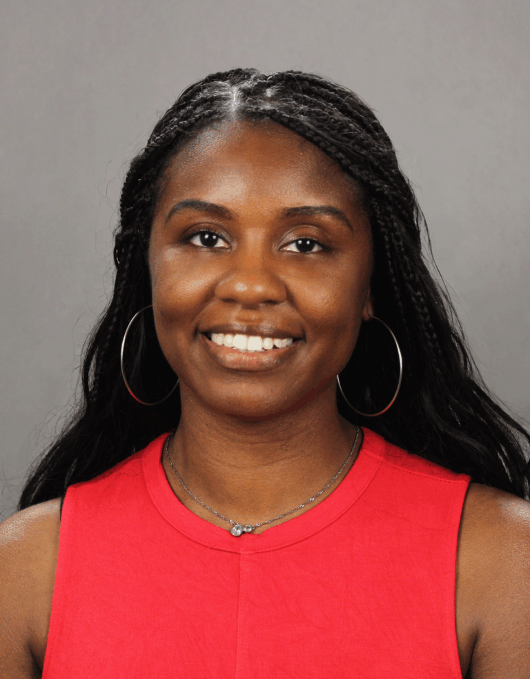 Woman in red shirt smiling, posing for photo.