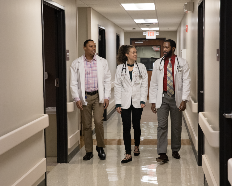Three doctors in a hospital hallway.