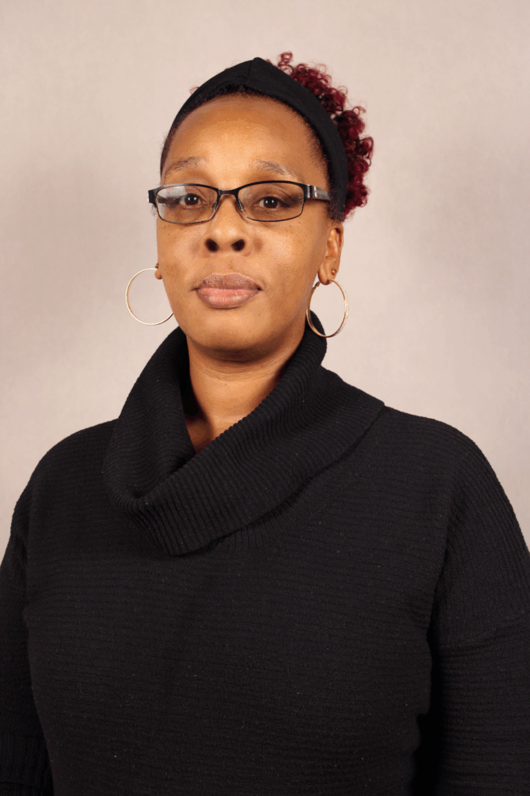 Woman in glasses, black coat, and earrings.