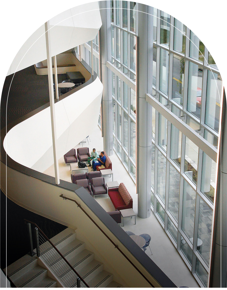 A spacious, modern lobby with a curved staircase and a large window.