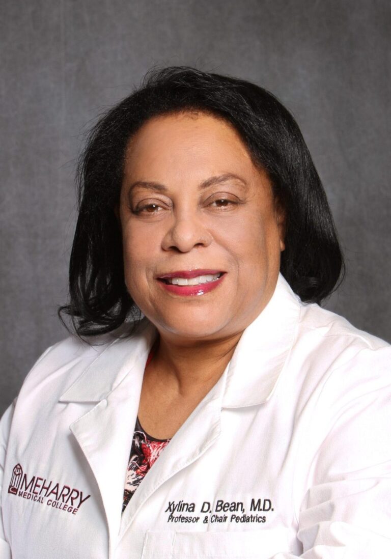 Woman in white coat, smiling, posing for portrait.
