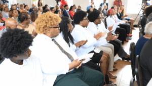A group of people sitting in a room, clapping.